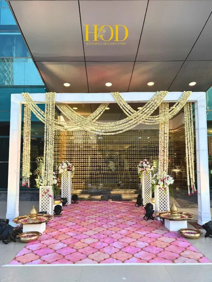 A clean and elegant entrance for a daytime wedding ceremony. I used a simple white frame draped with jasmine garlands and a beautiful patterned floor covering to create a sophisticated and welcoming entryway for guests.
