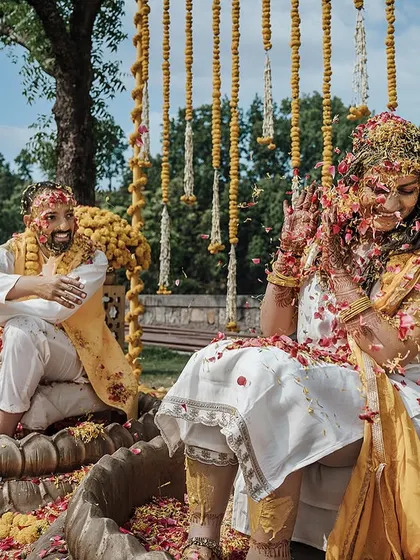 The bride gets playfully showered with flower petals by her family and friends during her Haldi.