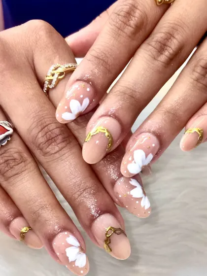 Another angle of the elegant floral and gold nail set, showing how the light catches the subtle gold shimmer and highlights the hand-painted white flowers.