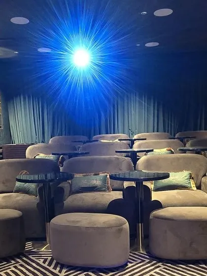 A duplicate of 79, this image captures the dramatic moment the projector beam hits the screen, illuminating the unique seating arrangement.