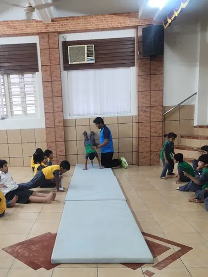 A full view of our kids' gymnastics session. We use mats and provide hands-on support to ensure a safe environment for children to learn foundational movements like handstands and rolls.