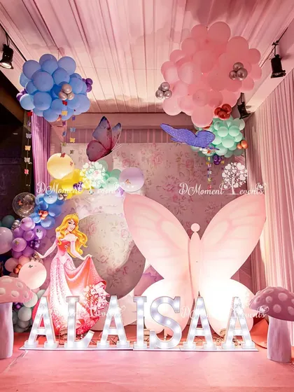 A magical photo corner featuring a princess cutout, light-up name display, and a giant illuminated butterfly wing, creating a perfect spot for memorable pictures.