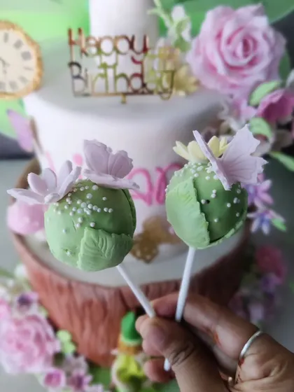 A whimsical Tinkerbell-themed birthday cake. This custom creation includes matching cake pops, showing how we can create a full dessert spread for a themed party.