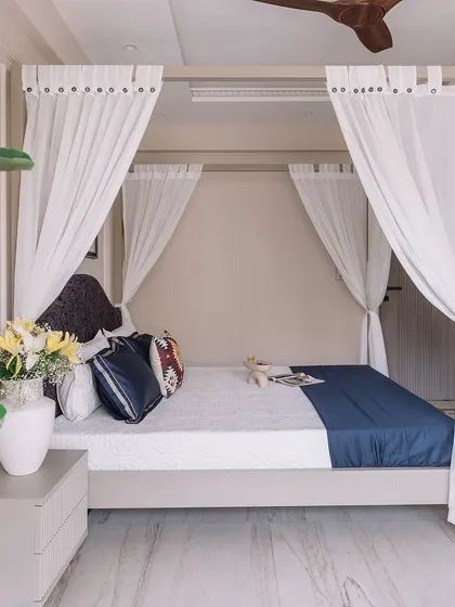 The centerpiece of our 'Modern Muse' project bedroom: a custom-designed four-poster bed draped with sheer white curtains, creating a romantic and ethereal focal point.