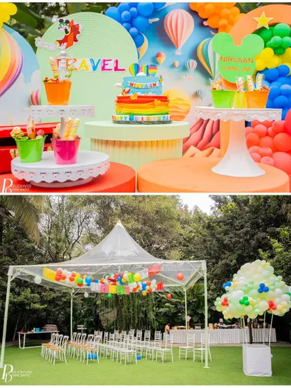 A wider view of the travel-themed party, showing the dessert table and the outdoor seating area under a tent.