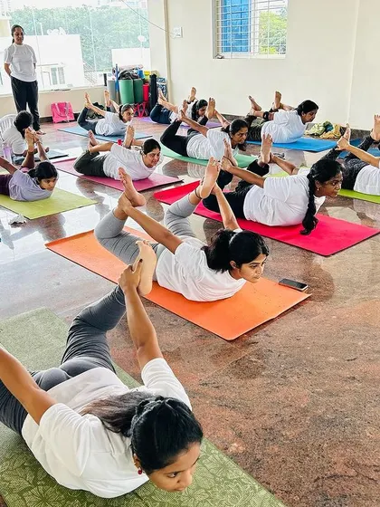 A full class of dedicated students moving together in Dhanurasana, or Bow Pose. This image captures the collective energy and focus we cultivate in our group sessions, where everyone supports each other's practice.