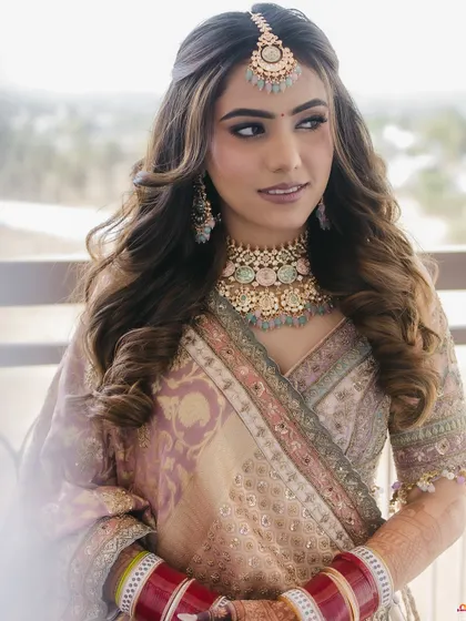 A stunning pastel bridal look with soft waves and a maang tikka, perfect for a modern bride.