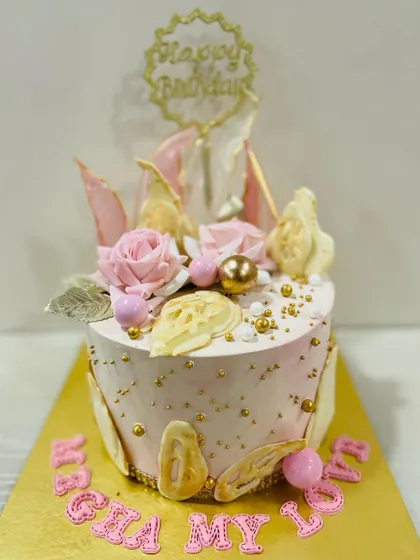 An elegant pink cake with abstract white chocolate sails and delicate pink roses.