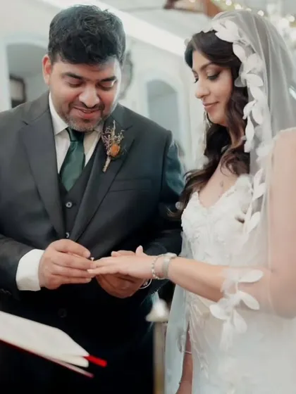 A precious moment of the ring exchange. The bride's soft hairstyle and makeup look timeless and elegant in this classic church setting.
