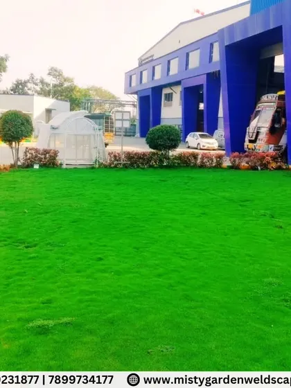 A wide view of the completed lawn at Mother India Farming, creating a beautiful green foreground for the commercial building. A well maintained landscape enhances corporate premises.