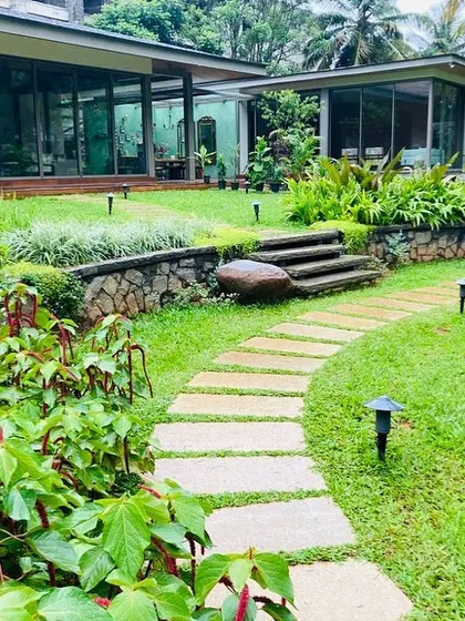 The design incorporates natural elevation changes with stone retaining walls and steps, creating distinct levels and adding visual interest to the large garden space.