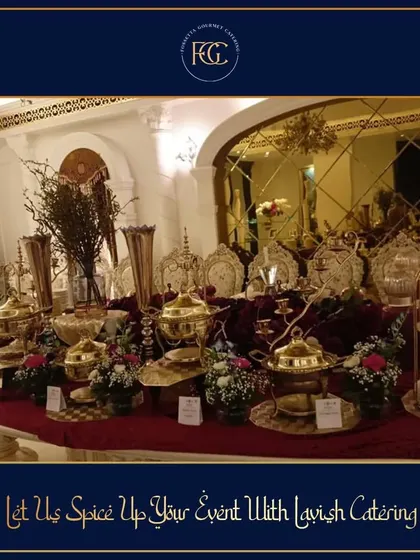 A lavish buffet table against a backdrop of gold-mirrored walls. The setup is dense with ornate brass serving dishes, candelabras, and floral arrangements, perfect for a grand, royal-themed wedding.