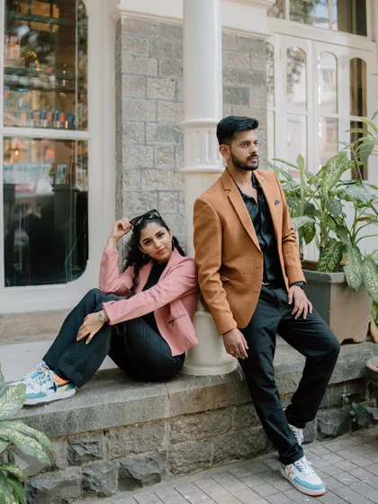 A fashionable portrait of a couple posing against a pillar in front of a building. This shot has a cool, editorial feel, perfect for a modern save the date.