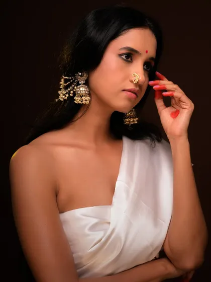 A beautiful and serene ethnic portrait. The model's traditional jewelry and gentle expression are highlighted by warm, soft lighting.