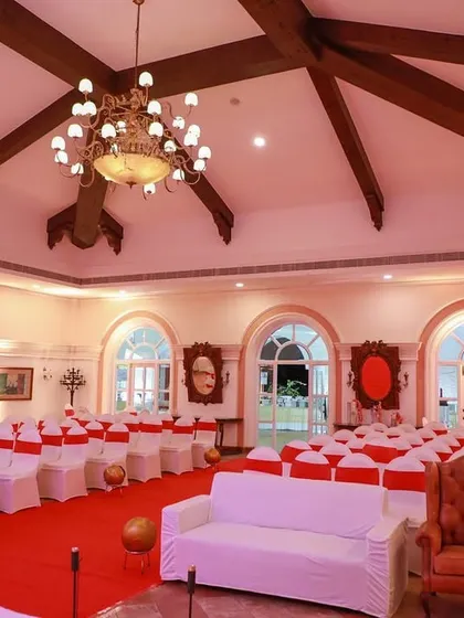 The indoor seating arrangement for the 'MAISHA' reception. The hall's grand architecture with high ceilings and chandeliers was complemented by our choice of red and white themed seating.
