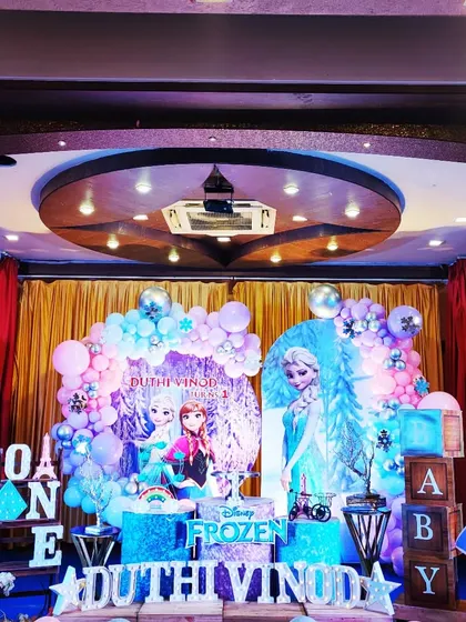 An elaborate Frozen-themed first birthday for Duthi Vinod. This large-scale setup includes multiple character cutouts, two backdrops, and plenty of icy blue and purple balloons.