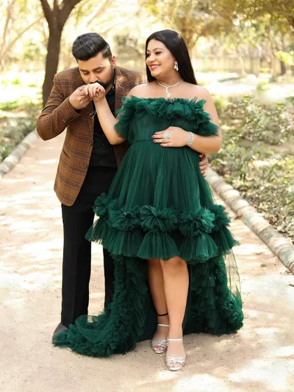 An outdoor maternity photoshoot is perfect for capturing love in a natural, romantic setting. Here, a gentle kiss on the hand in a beautiful park setting tells a story of love and anticipation.