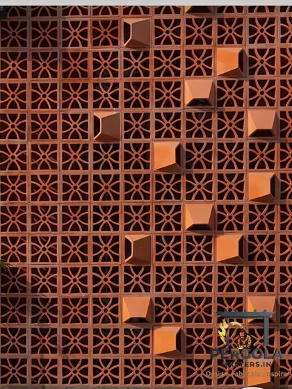 A close-up of a terracotta jali wall, showing the detail of the pattern and the natural, earthy texture of the clay blocks.