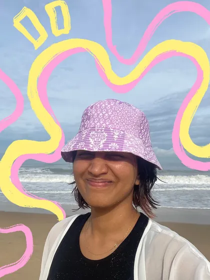 A happy beach selfie with a bucket hat, made even brighter with some abstract pink and yellow doodles.