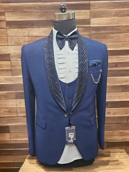 A blue three-piece suit in a textured fabric with an embellished lapel. A great choice for a wedding guest.