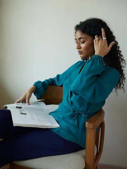 This shot captures the model engrossed in a magazine, creating a natural and relatable lifestyle moment. It showcases the outfit in a context that feels authentic and unposed.