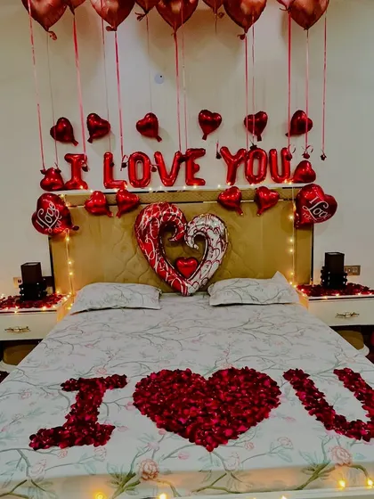 Another perspective of the bed, focusing on the "I heart U" message created with fresh rose petals, surrounded by heart-shaped balloons and soft lighting.
