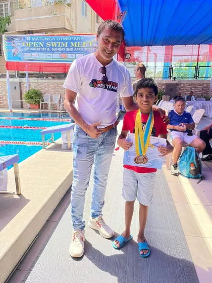 Success across multiple events is a hallmark of a well-rounded swimmer. Here, Bryce is pictured with his coach at the Matunga Gymkhana swim meet after winning medals in breaststroke, butterfly, and the individual medley (IM), demonstrating his proficiency in various strokes.