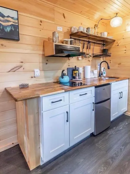 This rustic-style kitchen in a wooden cabin shows how we can tailor the design to any aesthetic. It features a compact fridge, induction cooktop, and open shelving for a cozy, cabin feel.