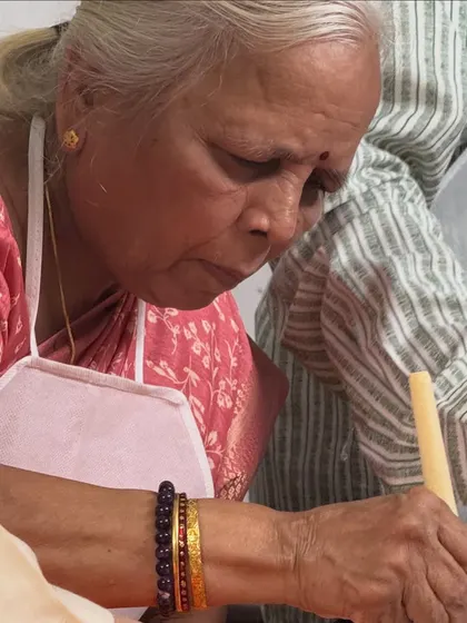 A grandmother fully engaged in painting a large collaborative canvas with her family. Art is truly for all ages.