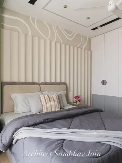 This bedroom is a quiet conversation between textures and tones. A calming palette of sage green, soft greys, and warm beige forms the base, while the fluted headboard and fluid wall pattern add depth and dynamism.