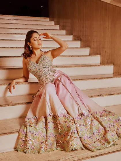 A beautiful shot of Nushrratt Bharuccha seated, showcasing the stunning floral embroidery on the skirt of this pastel lehenga.