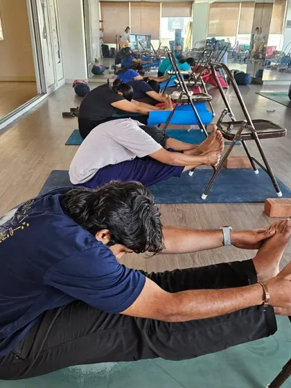 Our TTC students learn to use props like chairs to make poses more accessible. Here, they practice Paschimottanasana (Seated Forward Bend) with chair support to deepen the stretch safely.