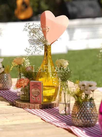 A close-up of a picnic table centerpiece with vibrant pink vases and fresh flowers.