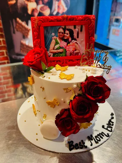 A heartfelt birthday cake for the "Best Mom Ever," featuring a cherished photo in a red fondant frame and decorated with fresh roses.
