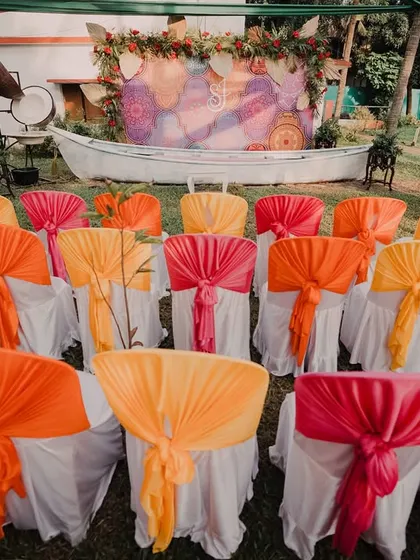 Brightly colored drapes on chairs add a pop of festive energy to this outdoor Mehendi event seating area.