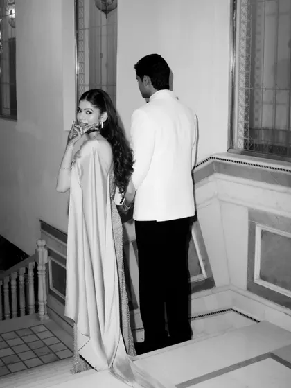A candid black and white shot of the couple walking down a staircase, the bride glancing back with a playful look.