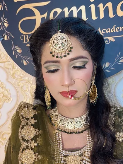 A front-facing portrait of the bride in her olive green attire, showing the complete makeup with a focus on the dramatic eyes.