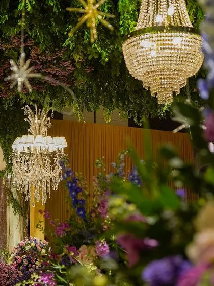 A detail shot looking up at the crystal chandeliers and hanging stars through a cascade of purple and blue flowers. This image captures the magical, dreamlike quality of the decor.