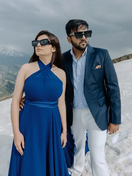 A stylish, fashion-forward portrait of the couple in the snow. The sunglasses and confident poses add a touch of modern glamour to the rugged mountain landscape.