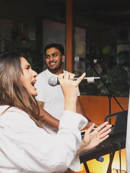 Shanelle and Aryaman singing together while Brendan smiles from the keyboards. These candid moments capture the joy we feel when we perform.