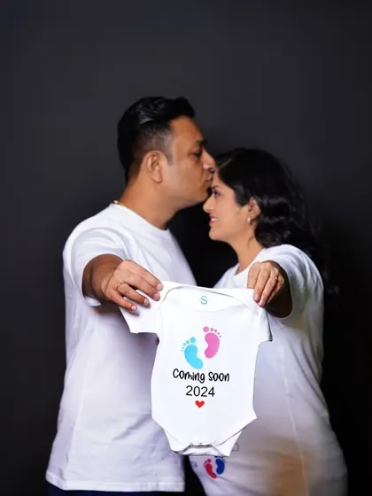 A sweet and symbolic photo of a couple holding up a "Coming Soon 2024" baby onesie. This is a popular and adorable way to announce your pregnancy in a studio session.