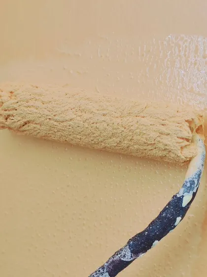 A close-up of a texture roller in action. Using the right tools is essential for achieving the desired effect, whether it's a smooth finish or a decorative texture.