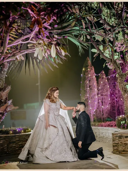 A classic romantic pose, with the groom kneeling to kiss his bride's hand.
