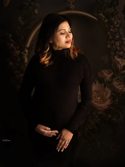 A moody and artistic portrait. The low-key lighting and floral background create a beautiful, painterly effect in this shot.