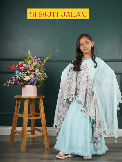 This little girl is wearing my sky blue cape set, a truly magical outfit. The flowing cape with floral prints and tassels makes it a standout piece for any special event.