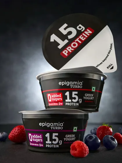 A close-up of Epigamia's Turbo Greek Yogurt, stacked to create a heroic composition. The partially peeled lid adds a dynamic element, inviting the viewer to imagine opening the product.