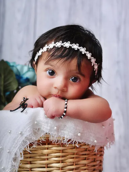 Those big, curious eyes are the center of attention. This alert baby peeks over the edge of a basket, showing off their budding personality in a simple and sweet setup.
