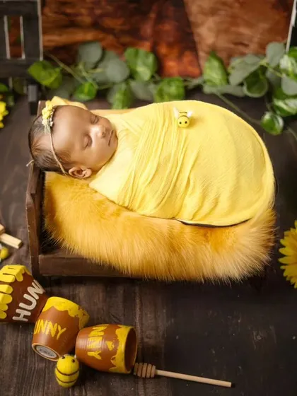 Our sweet little honeybee, all snuggled up. This themed newborn session includes a custom backdrop, honey pots, and adorable bee props for a truly unique portrait.
