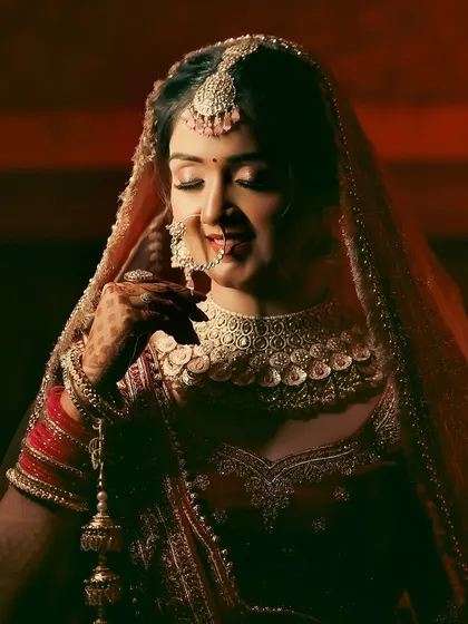 A lovely bridal portrait with warm, dramatic lighting. The bride's gentle smile and the focus on her intricate choker necklace make this a captivating shot.