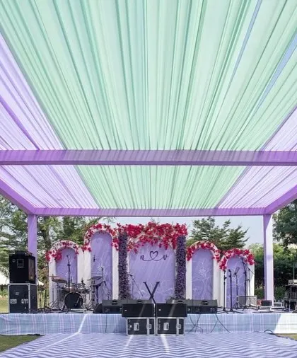 A beautiful stage setup for a Sangeet or Haldi, with a performance area under a canopy of lilac and mint green drapes.